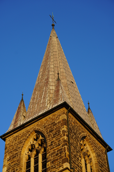Foto einer Kirchturm-Spitze im Sonnenlicht vor strahlend blauem, wolkenlosen Himmel.