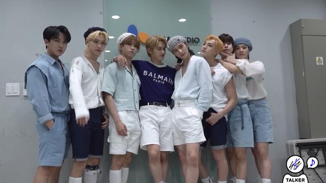 skz members pose for a photo. Hyunjin's looking at the camera. Lee Know's looking at Hyunjin with an expression of satisfaction.