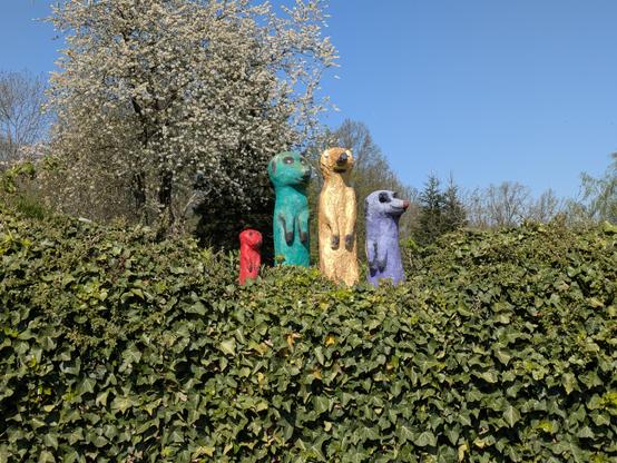 Figuren von Erdhörnchen auf einer bewachsenen Mauer.