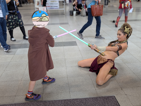 A young Jedi standing over Slave Leia back on her knees in the midst of a lightsaber duel.