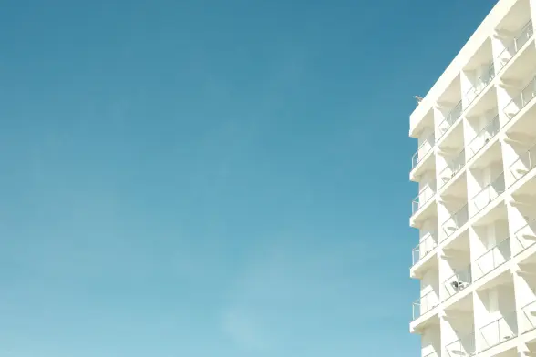 White hotel building balconies against a clear blue sky
