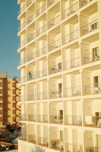 Sunlit hotel balconies with people relaxing outside