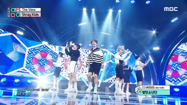 Stray Kids performing on stage while wearing sailor-style outfits with shorts.