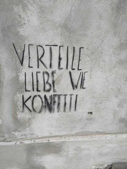 Graffiti auf einer grau verputzen Wand: "Verteile Liebe wie Konfetti"