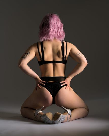 Eine sportliche, Muskolöse Frau kniet am Boden. Man sieht ihren muskolösen Rücken.