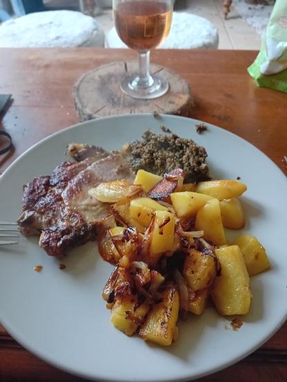 Cotés de porc, algues et chou rouge, pommes de terre et oignons dans une assiette grise