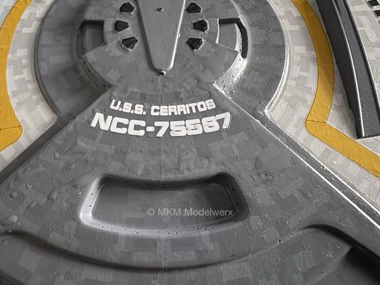Dark grey area of the top of the model with white text that reads “U.S.S. Cerritos” and underneath “NCC-75567”