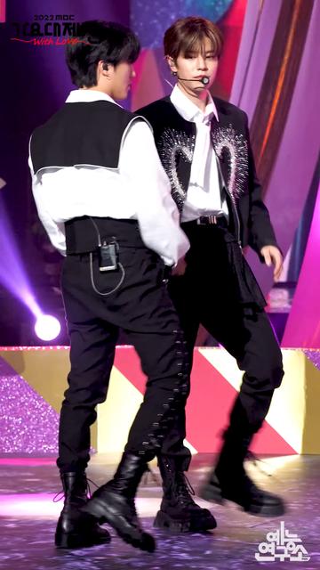 Changbin and Seungmin standing at the side of the stage during a performance of Circus. Seungmin has a black scarf attached to his left hip.