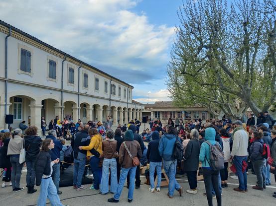 Un spectacle dans la cour de l'école publique élémentaire. On y voit une foule de dos en train de regarder un spectacle.