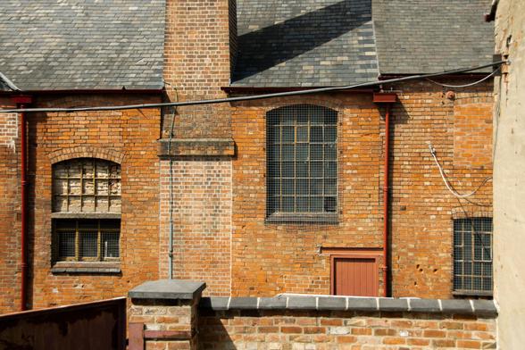 A close-up of the brick exterior with windows and red drainpipes.
