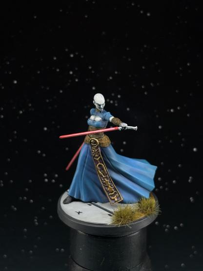 Asajj Ventress miniature from Star Wars shatterpoint with a blue cloak, golden and brown decoration, pale skin and a pair of red lightsabers