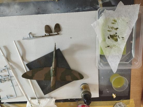 Maqueta de un Spitfire MkI vista desde arriba recien pintada en verde oscuro 71324 de Vallejo. Al lado, una paleta húmeda casera para mantener la pintira fresca.