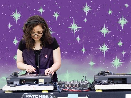 Hintergrund: lila mit weissen Sternen
DJ Vulverine am Turntable hinterm DJ Pult