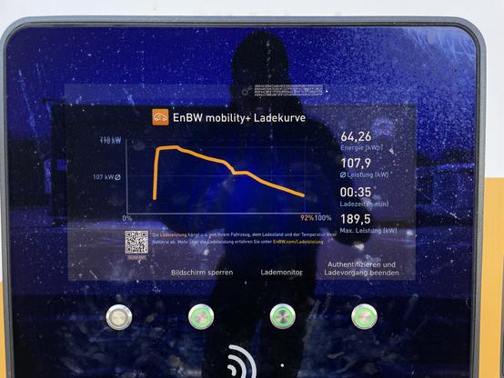 Das Bild zeigt eine digitale Anzeige einer Ladestation, die von EnBW Mobility+ betrieben wird. Die Anzeige hat einen blauen Hintergrund mit einem orangefarbenen Grafik, der die Ladegradkurve zeigt. Auf der linken Seite des Bildschirms ist ein Graph zu sehen, der die Leistung in kW von 0 bis 189,5 kW und die Energie in kWh von 0 bis 64,26 kWh darstellt. Rechts neben dem Graph sind verschiedene Werte angezeigt: Energie (64,26 kWh), Leistung (107,9 kW), Ladezeit (00:35 Minuten) und Max. Leistung (189,5 kW). Darunter befinden sich drei Buttons: "Bildschirm sperren", "Lademonitor" und "Authentifizieren und Ladevorgang beenden". Der Hintergrund des Bildschirms zeigt eine schematische Darstellung eines Menschen vor einer dunklen, sternenartigen Hintergrund.

Bereitgestellt von @altbot, privat und lokal generiert mit Ovis2-8B

🌱 Energieverbrauch: 0.294 Wh