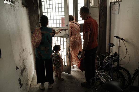 A backlit picture of 3 adults and a child preparing to walk through a door