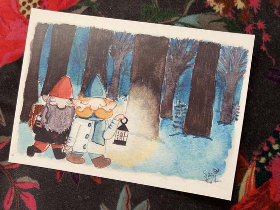 Art print of a watercolour painting of two gnome husbands walking through the woods at dusk. The gnome with the red hat and beard is carrying a pack of freshly cut logs for their cottage, and the gnome in the blue hat with the moustache lights the way with a lantern.