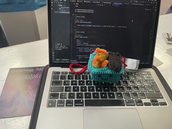 Ein gehäkeltes Dumpsterfire auf einem Laptop auf dem mehrere PHP-Dateien des Engelsystems geöffnet sind.