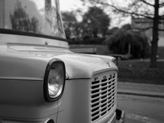 Black and white photo of the front hood of an old Ford van.