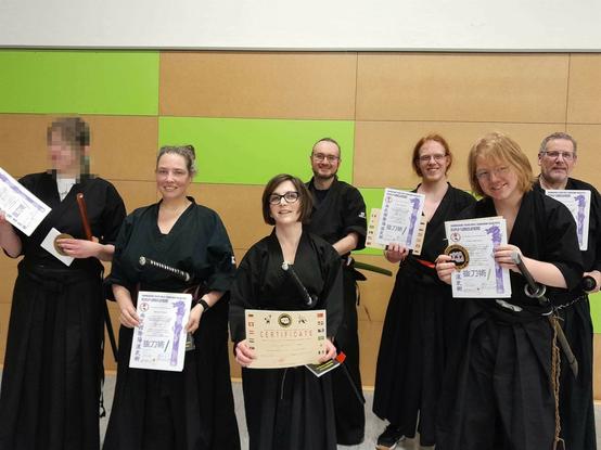 7 people cheering with their new certificates. One does not have a certificate, but the others do.