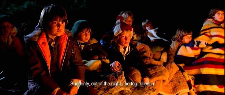 A group of children wrapped in blankets listen attentively around a fire. “Suddenly, out of the night, the fog rolled in.”