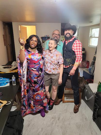 A group of four smiling people of all shapes, sizes, colors, and genders pose in a literal rainbow of colorful clothing.
