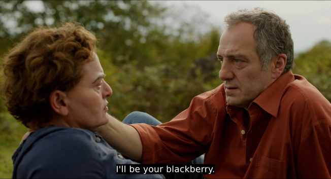 A screenshot from the film Blackbird Blackbird Blackberry with Murman holding Etero's face while saying "'I'll be your blackberry"