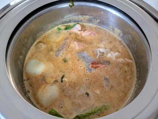 Tom Yum hot pot soup with fish balls, salmon, shrimp and greens.