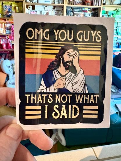 a hand holding a piece of paper, on which is painted jesus, with his hand on his face, and the text "OMG you guys, that's not what i said"