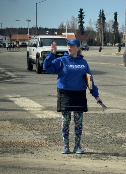 It's me in my wildly colored pants, skirt and I Dissent sweatshirt standing almost in the highway signaling the most recent count of attendees at the protest.