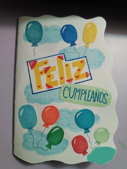 Fotografía de la portada una tarjeta de feliz cumpleaños que hice para mi novio. Dice "feliz cumpleaños" y tiene globos de colores a su alrededor, con nubes de fondo