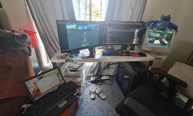 photo of my PC setup with a bonus cat! On the left is a Windows 7 Dell laptop, my main PC is in an almost 15 year old HAF-X case, on the right is a 2002'ish CRT monitor with a Wings of Fire plush on top, and is displaying SecondLife on the monitor