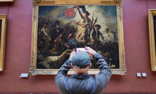 Un turista fotografía La Libertad guiando al pueblo, el cuadro de Eugène Delacroix en el Museo del Louvre (Pierre Crom)