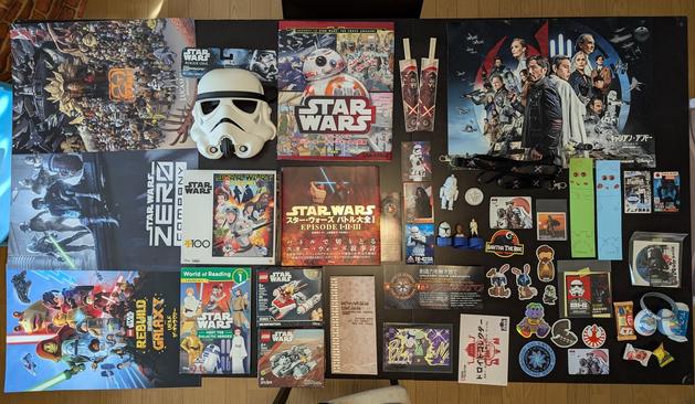 A collection of Star Wars posters, books, stickers, cards, bottle caps, Lego, and more organized on a dining room table.