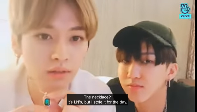Lee Know and Changbin on a livestream. Lee Know holds up a green pendant and says, "The necklace? It's I.N's, but I stole it for the day."
