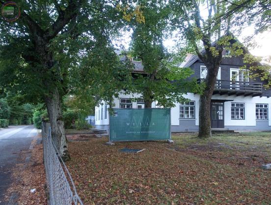 Ehemaliges Gasthaus mit Immobilienentwicklerbanner davor im Garten