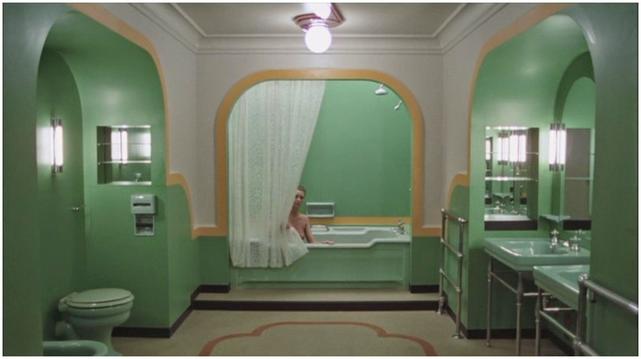 still from stanley kubrick's film, 'the shining', shows the art deco marvel that is the bathroom suite of room 237. a young woman sits in the bath, peering from behind the shower curtain.