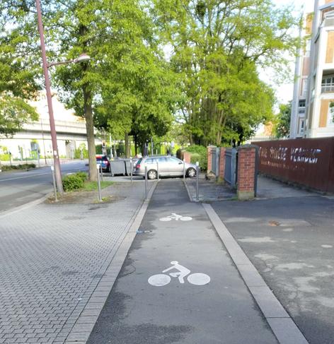 Une piste cyclable avec au loin une voiture en travers barrant la piste.