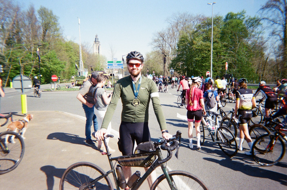 Myself in green bike jersey wearing finisher medal holding bike. Surrounded by many other people with bikes in background
