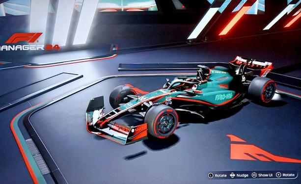 Screenshot of an F1 car in a showroom. The car is grey-green and black with red highlights. The Asticassia emblem is on the showroom floor.