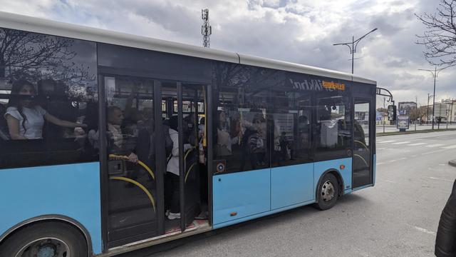 An entirely overcrowded, small blue bus.