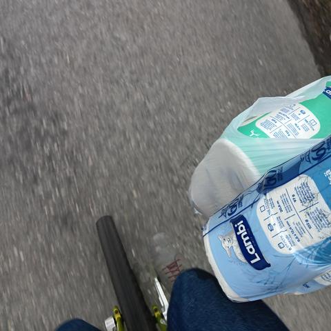 A view from the rider's perspective, looking down at the wheel of a unicycle. There is a shopping bag in the rider's right hand.