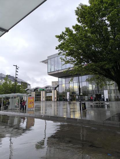 Blick auf den Bahnhof in Nantes. Der Boden ist sehr nass vom Regen und der Himmel ist grau bewölkt.
