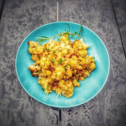 Cauliflower with chives and spring onion and a twig of rosemary in a blue plate