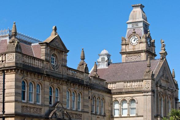 A colour photograph of Weston-super-Mare Town Hall, a stone building. Taken on a blue sky, sunny April day at around 13:19 hours - so the clock in the clock tower seems to be nine or so minutes slow.
