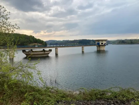 Über eine Brücke verbunden zeigt sich der Trinkwasserentnahmeturm sowie der Überlaufschacht in einer ruhigen See.