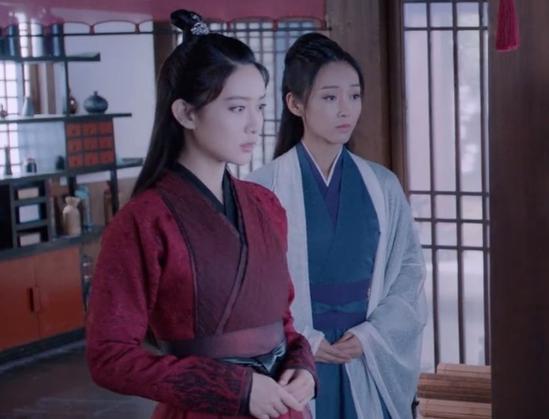 In the Wen supervisory office in Yiling, Wen Qing in flame embroidered Wen sect robes of red and black stands beside and slightly in front of Jiang Yanli in simple robes consisting of a sheer white overrobe worn loosely over layers of dark teal and indigo. Wen Qing's expression appears somewhat taken aback while Yanli's is sombre.