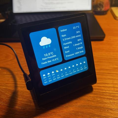 A Pimeroni Presto - a four-inch display and RP2350 microcontroller mounted on an elegant matte-black aluminium stand. The display is showing details of the current weather and forecast for the rest of the day. (Spoiler: It’s raining)