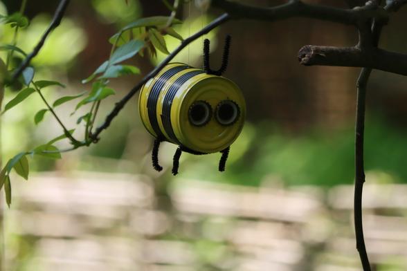 Eine fliegende Biene.
Der Körper eine gelb-schwarz angemalte Blechdose, zwei Kronkorken als Augen, schwarzer Bürstendraht als Beine und Fühler.