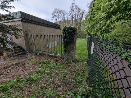A photograph of what is probably a works compound. In the foreground is a fence and on the left a gate which can be unlocked. To the right is a gap between one fence and another allowing anyone just to walk around and bypass the locked gate.