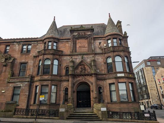 A red stone building with two turrets and a sign reading Sovereign House above the door